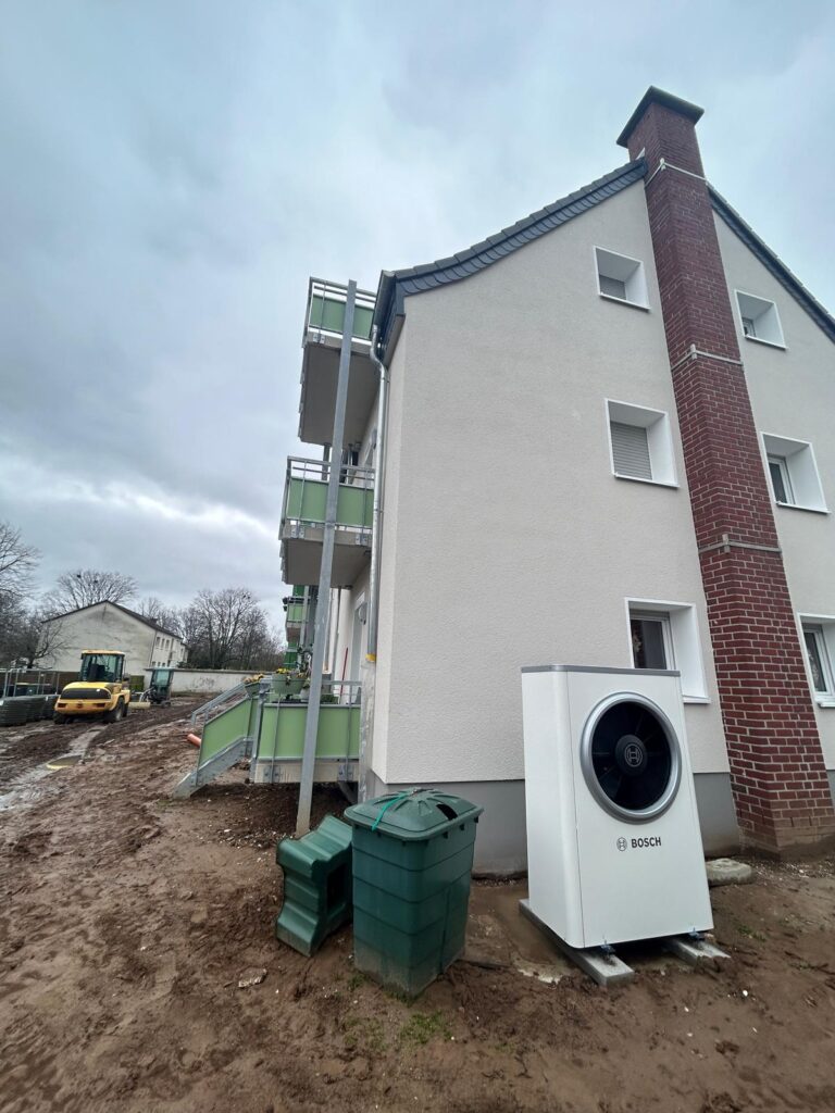 Mehrfamilienhaus mit Wärmepumpe in Seitenansicht kurz vor Fertigstellung